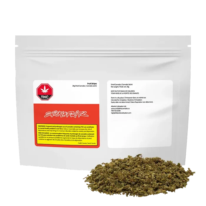 Front view of a white resealable pouch labeled "Fruit Stripez" with a red and yellow warning panel and a small pile of loose green herbal material in front.