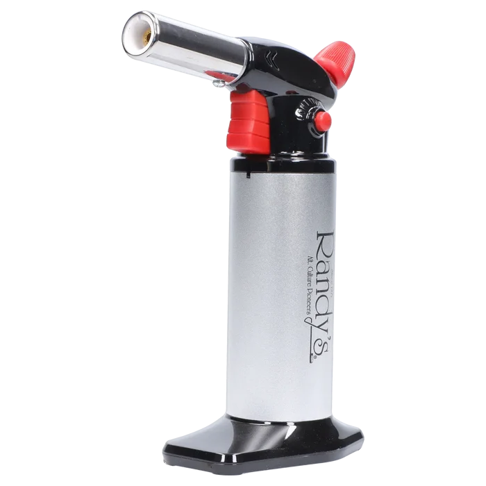 Close-up side view of Randy's Fahrenheit Butane Torch - Silver showing its angled chrome nozzle, red trigger and adjustment knob, and vertical silver body on a black base.